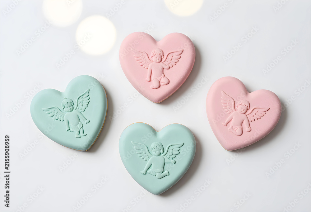 Fototapeta premium Pastel pink and mint green heart shaped cookies with cupid angel relief, valentines day dessert, isolated on white background