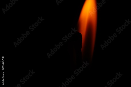Conceptual macro photograph of two matchsticks facing each other with a glowing flame in the background.