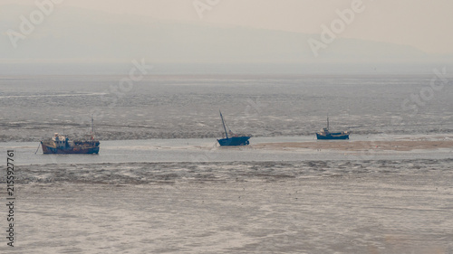 Boats moored on beach at low tide, Thurstaton, The Wirral, UK