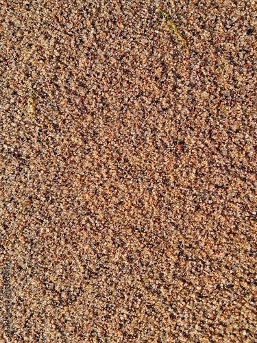 High angle view of coarse textured beach sand mixed with colorful tiny pebbles and grit on a sunny coast in Estonia.