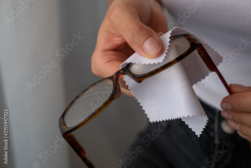Woman cleaning eyeglasses with microfiber cloth for lens care, hygiene and clear vision.