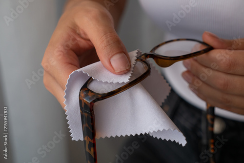 Woman wiping eyeglasses with microfiber cloth for lens cleaning and clear vision