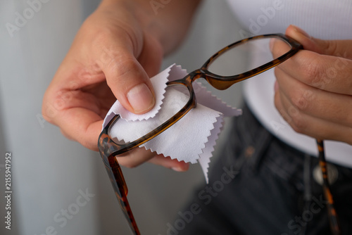 Woman cleaning eyeglasses with microfiber cloth for lens care and clear vision