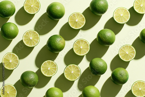 Fresh limes and lime slices arranged artistically with shadows.