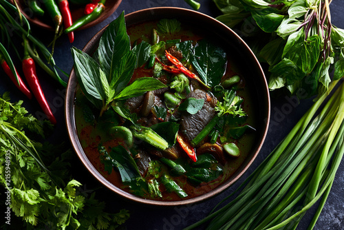 A vibrant bowl of spicy soup with fresh herbs and colorful vegetables.