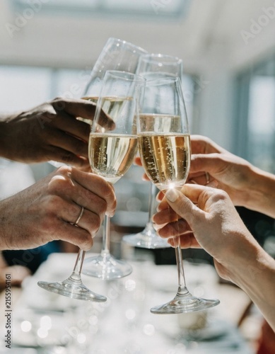 A group of hands raising champagne glasses in a joyful toast to celebrate significant milestones accomplishments and happy memories shared together