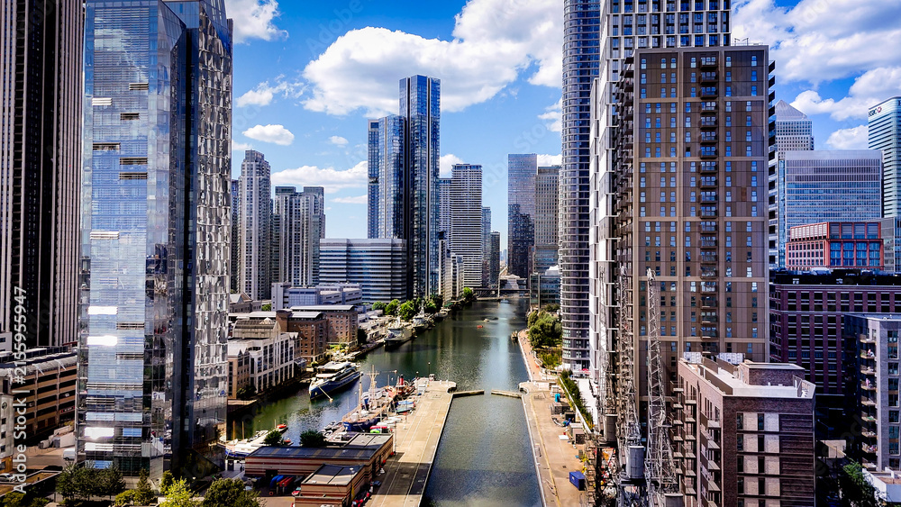 Obraz premium Aerial view between modern skyscrapers and waterways in Canary Wharf, showcasing the dense contemporary architecture of London's financial district.