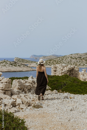 Canvastavla Woman in a black dress enjoying the scenic Adriatic coast among ancient stone ruins in Kornati, Croatia, surrounded by rocky islands, clear water and Mediterranean nature