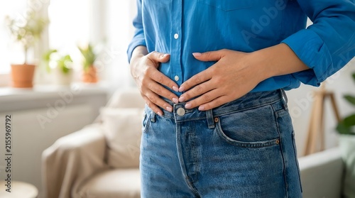 Woman holding her stomach and suffering from abdominal pain, bloating or indigestion at home