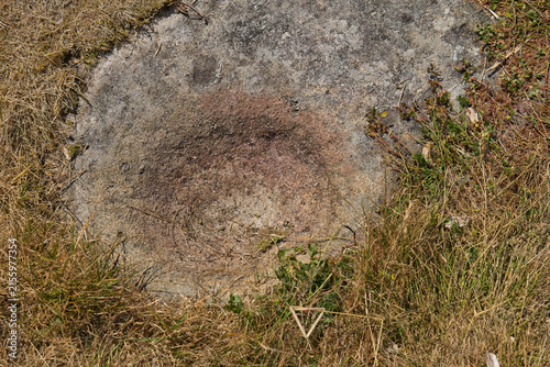 Fotografie A top-down view shows a circular, reddish-brown depression in a weathered grey r