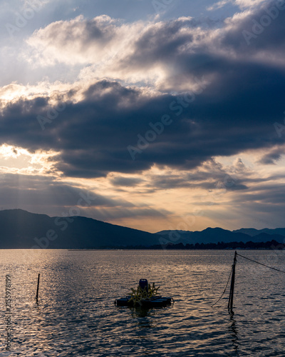 Foto Vertical view of wide lake under cloudy sky with sunbeams at sunset
