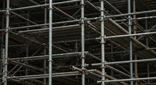 A complex network of metal scaffolding with wooden planks, used in construction.Concept of construction safety and temporary structures.