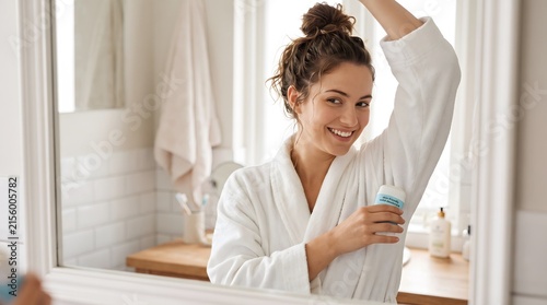 Woman in white robe applying deodorant to her armpit