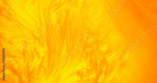 Shimmering gold abstract background. Liquid gold texture waves and swirls. Beautiful shiny yellow texture with glitter. Liquid gold metallic paint close-up.