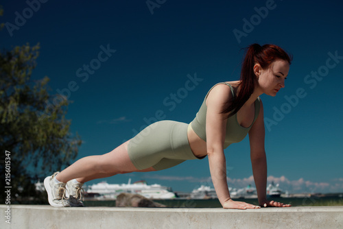 Woman Doing Push-Ups Outdoors Against Deep Blue Sky