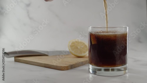 Adding more soda in glass. Cutting board with knife and lemon on back. Original sound. 24fps. Prores 422HQ