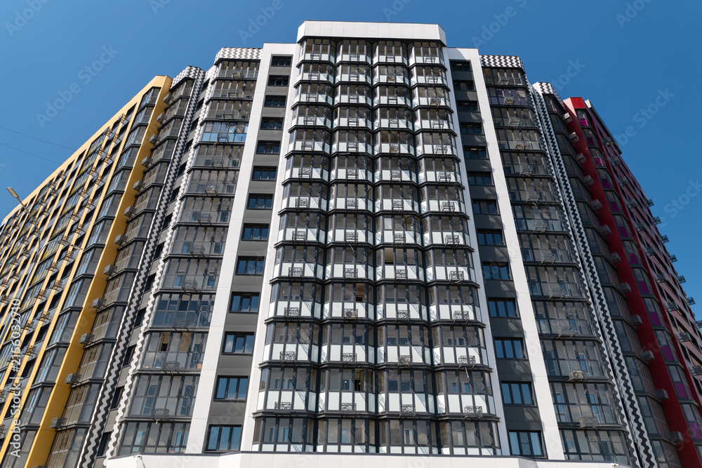 Fototapeta premium New apartment building with modern design showing multiple floors and balconies on a clear day in the city