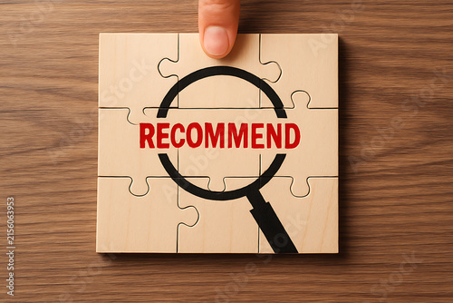 Jigsaw puzzle with a magnifying glass over the word recommend a conceptual photograph