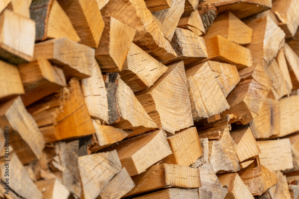 Fototapeta premium Stacked firewood logs texture background, chopped wood pile close-up, natural fuel material