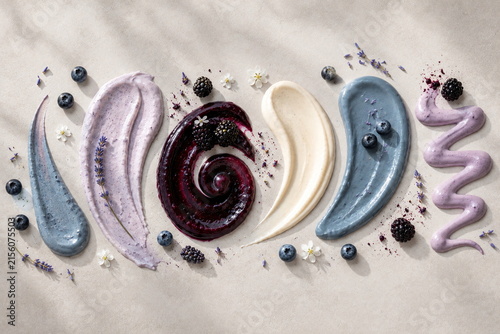 Elegant pastel assortment of blueberry, blackberry, berry cream and vanilla sauces decorated with fresh berries, lavender and flowers.