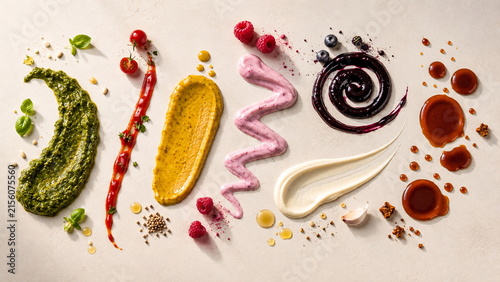Colorful assortment of gourmet sauces and condiments arranged as artistic smears on a warm neutral background.