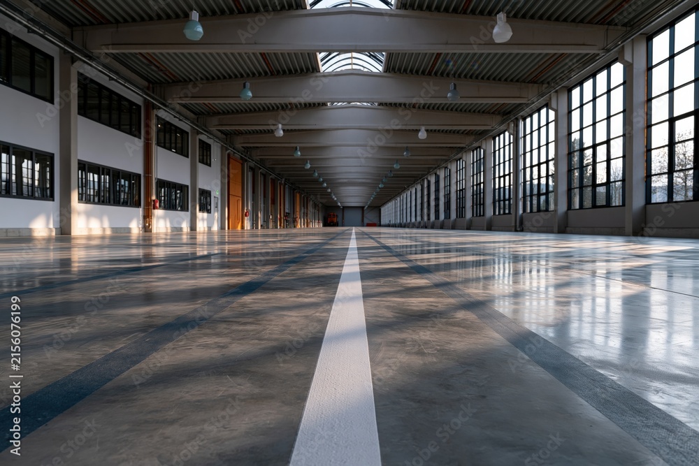 Fototapeta premium Long empty industrial hall with central white lane and large windows for commercial background and exhibition space banner