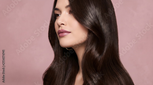 Pretty girl showing shiny brunette locks isolated on pink backdrop