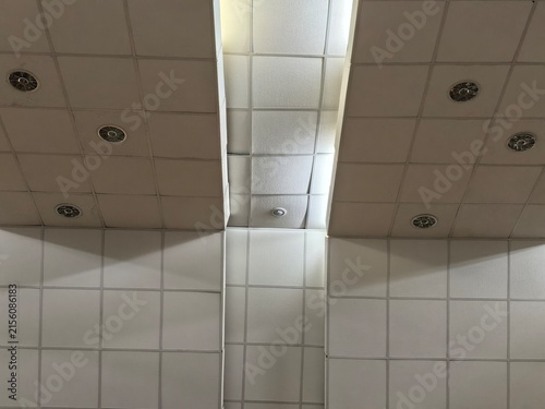 Suspended ceiling with fluorescent skylight panels and recessed ventilation fixtures in an institutional interior. Commercial architecture and building infrastructure concept.