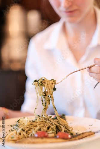 Frau sitzt als Gast im Restaurant und isst eine Speise Pasta