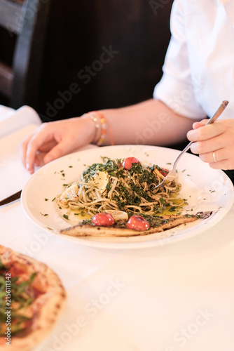 Frau sitzt als Gast im Restaurant und isst eine Speise Pasta