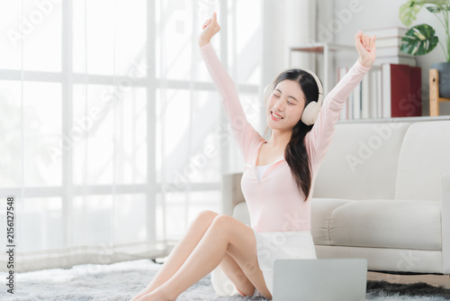 Foto Relaxing Afternoon: A young woman enjoys a moment of pure bliss, with arms outstretched and eyes closed, immersing herself in music through headphones