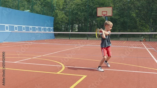 Young boy rehearsing tennis shots during court warm-up