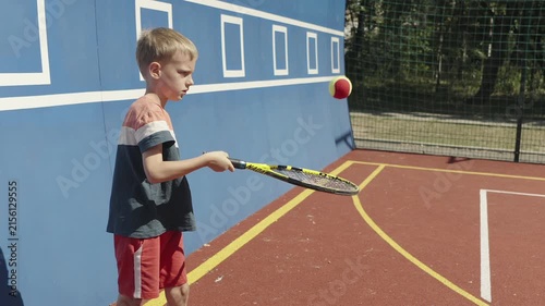 Young boy practicing tennis skills by bouncing a ball on his racket