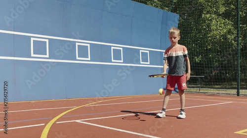 Young boy practicing tennis skills by bouncing a ball on his racket