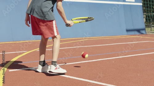 Young boy practicing tennis skills by bouncing a ball on his racket