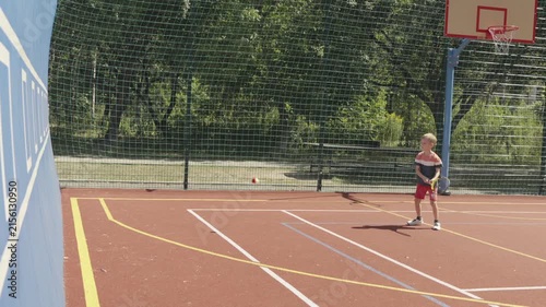 Slow motion. 7-year-old boy training his tennis skills against a practice wall