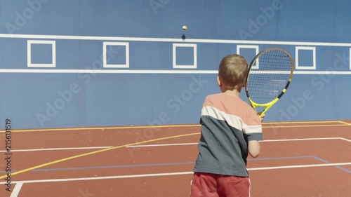 Slow motion. 7-year-old boy training his tennis skills against a practice wall