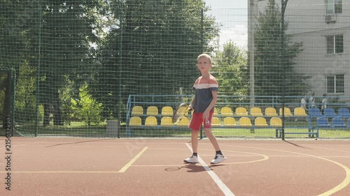 Slow motion. 7-year-old boy training his tennis skills against a practice wall