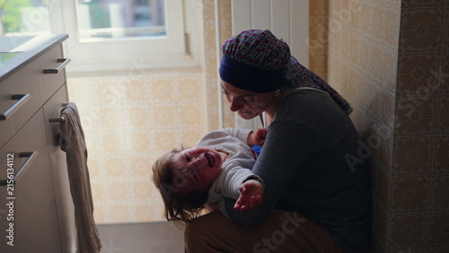 Fotografía Mother kissing distressed toddler while providing comfort and reassurance, tende