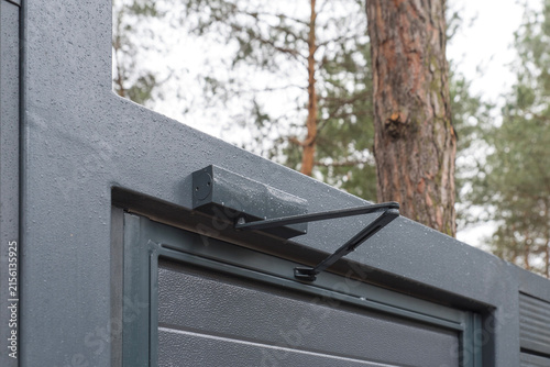 Fotografie Outdoor hydraulic door closer on gray metal gate frame