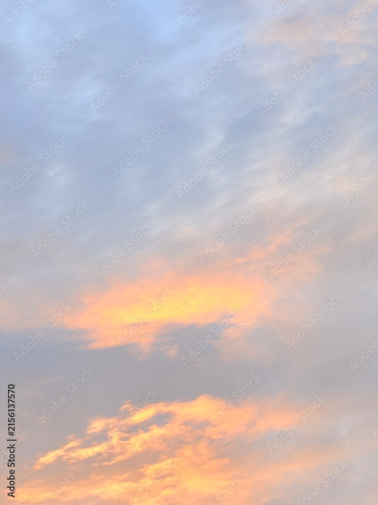 Fototapeta premium Glowing Orange Clouds Among Soft Gray Layers in a Vertical Sunset Sky