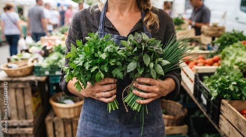 Fototapeta kuchenna A vendor proudly displays fresh, vibrant herbs and leafy greens at an outdoor market, surrounded by colorful produce.