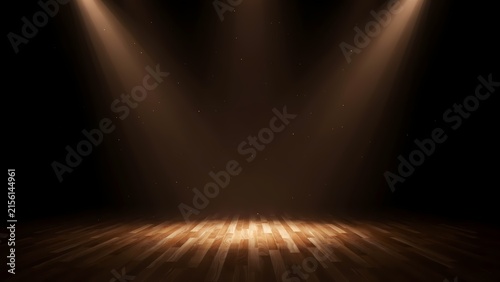 An empty wooden floor stage illuminated by dual overhead spotlights producing dramatic light beams and dust motes floating in the dark atmosphere creating a mysterious and theatrical setting