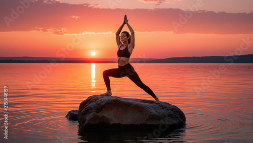 Asian woman doing yoga in a room with sunlight coming through the window.
