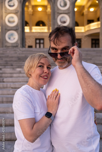 Foto Happy middle aged couple in white blank t-shirts hugging on river embankment ste
