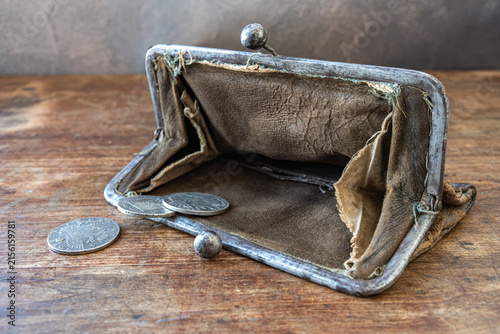 Canvas Print Opened old empty wallet with scattered coins on a rustic wooden table