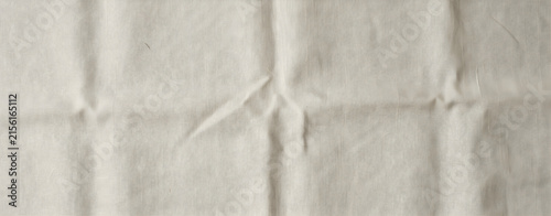 Natural beige linen fabric background texture with soft folds and creases, empty cloth material for design backdrop or wallpaper