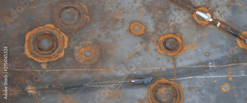 Detailed closeup of weathered industrial metal surface featuring rust spots, corrosion patterns, welding seams, and oxidation textures for abstract backgrounds