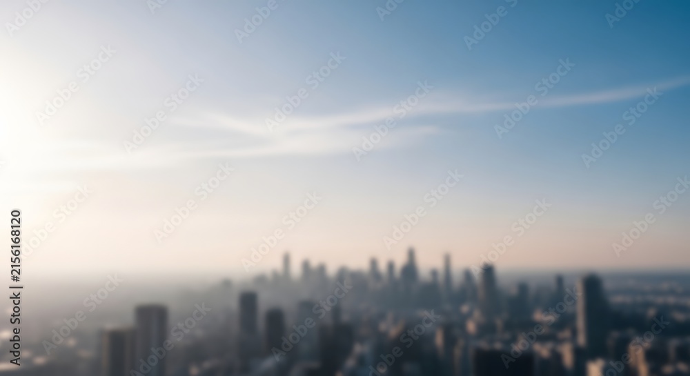 Fototapeta premium City skyline rises under a clear horizon during a bright hazy day in a blurred panorama.
