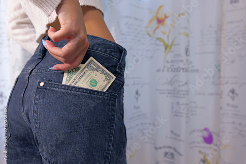 Woman putting dollar bill into back pocket of jeans